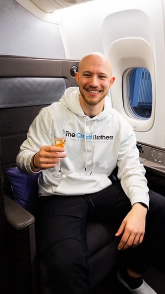 Josh Steil in the ANA first class seat with a glass of champagne