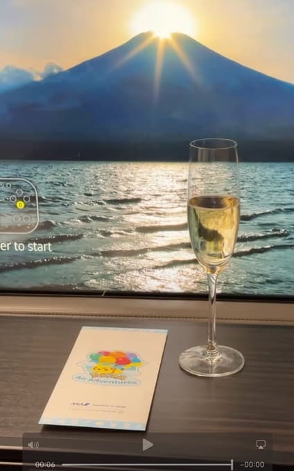 Mount Fuji at sunrise on the seatback screen, beside a champagne flute