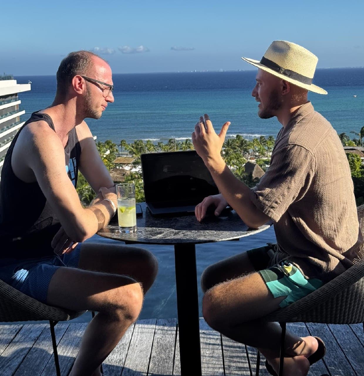 Josh and Chris working at a rooftop table overlooking the ocean